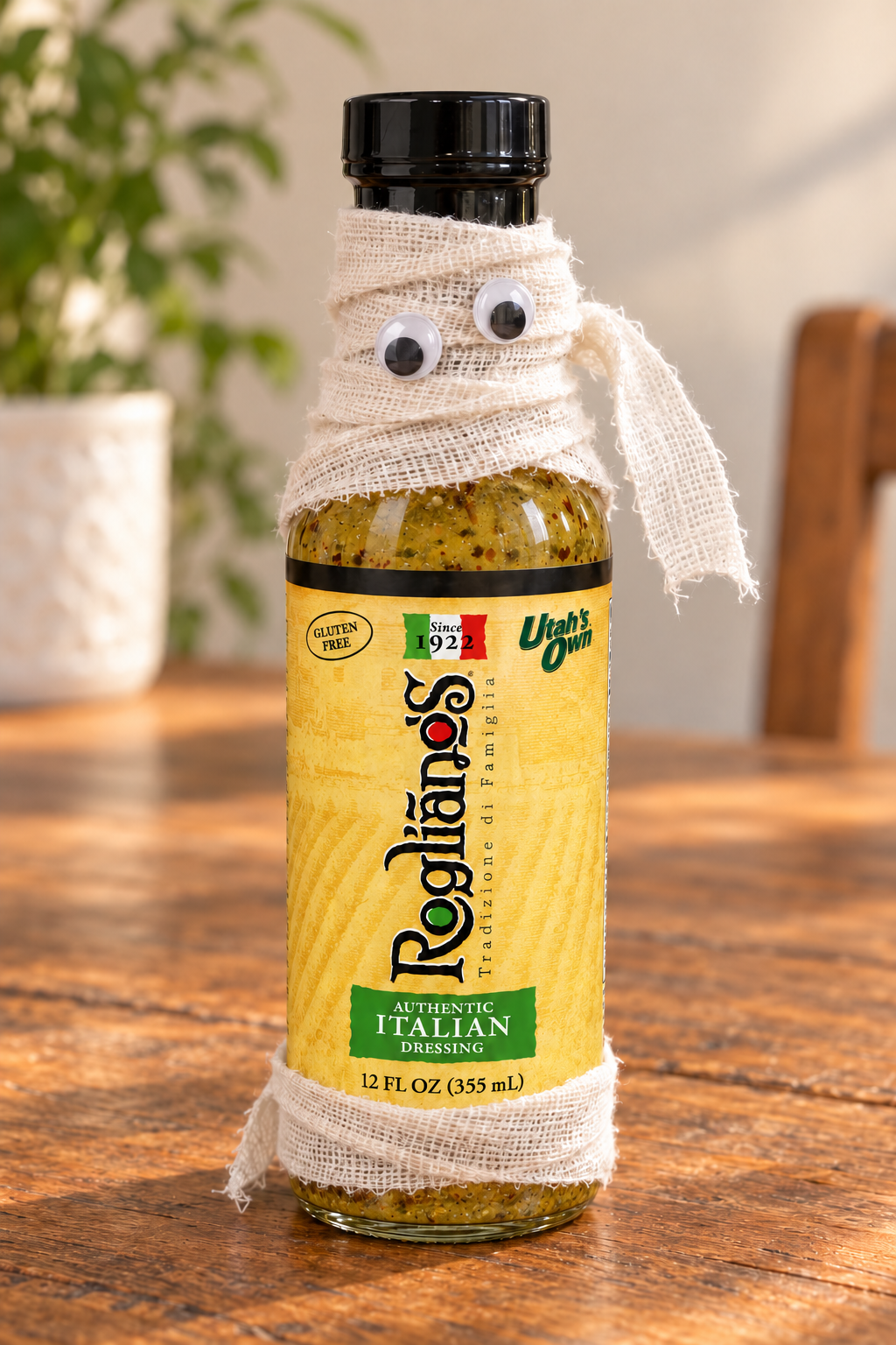 A full Authentic Italian bottle with a loose white gauze face, two googly eyes and a gauze band near the base; the label and cap remain visible.