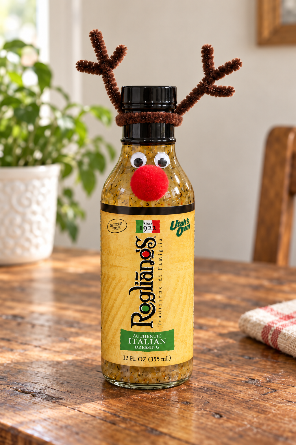 An Authentic Italian bottle dressed as Rudolph with brown chenille antlers, two googly eyes and a red pom-pom nose.