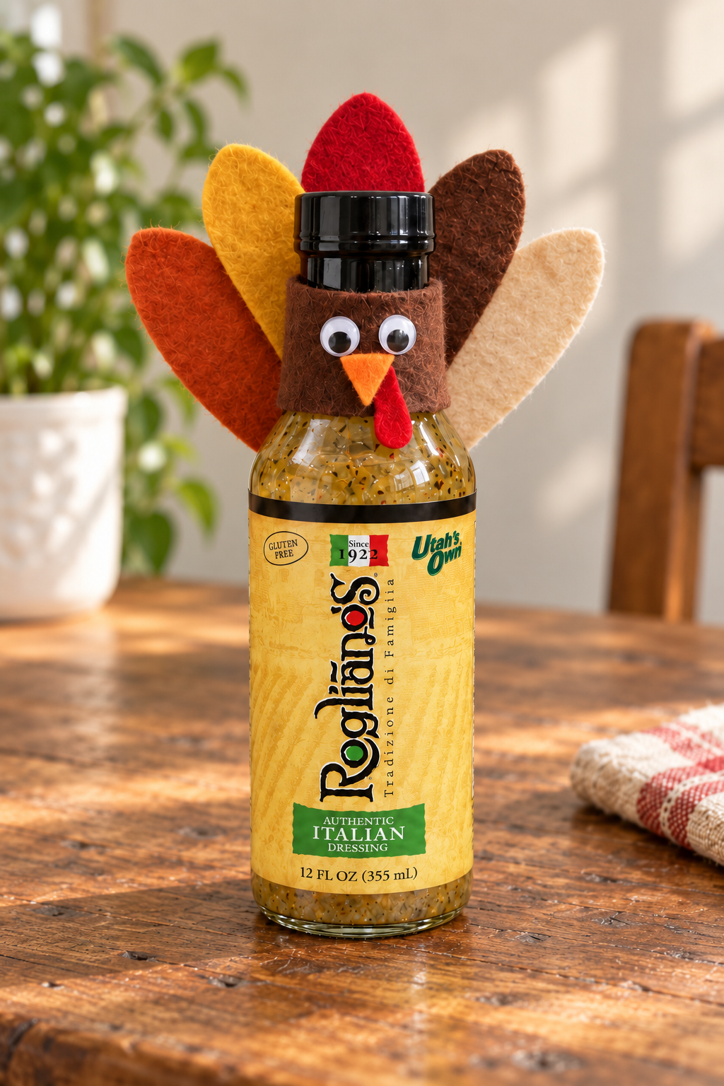An Authentic Italian bottle dressed as a turkey with five autumn felt feathers, a brown felt face collar, googly eyes, an orange beak and a tiny red wattle.